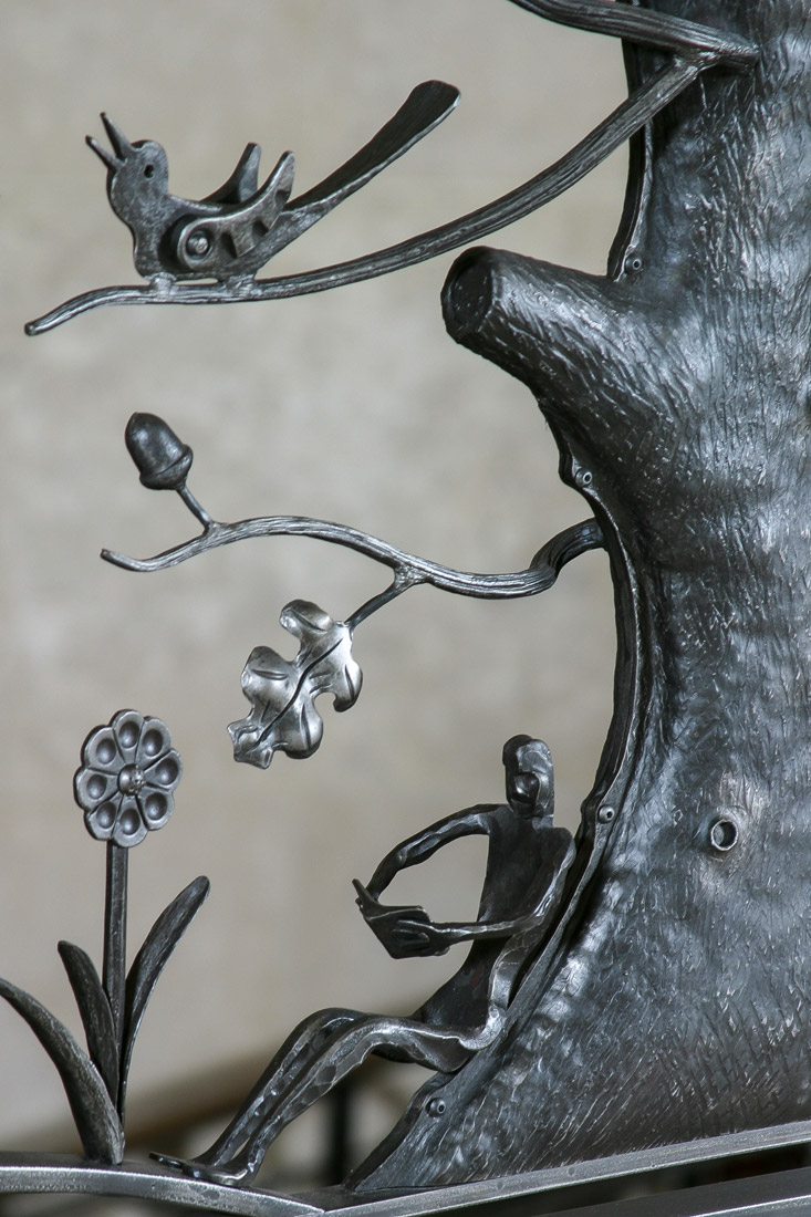 detail of artistic iron railing with bird chirping and man reading book