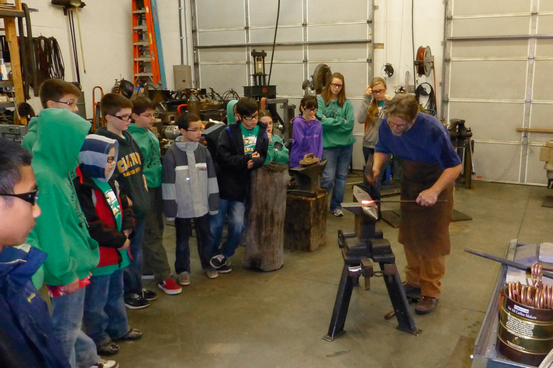blacksmith glenn gilmore demonstrates for a group of young students
